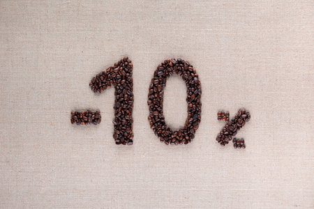 Roasted coffee beans shaping 10% off writing on creamy linen background in centerの写真素材