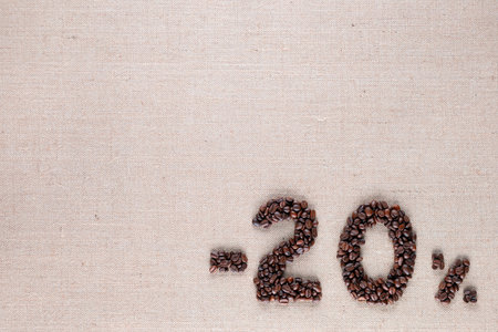 Roasted coffee beans shaping 20% off writing on creamy linen background, aligned bottom rightの写真素材
