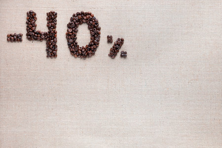 Roasted coffee beans shaping 40% off writing on creamy linen background, aligned top leftの写真素材