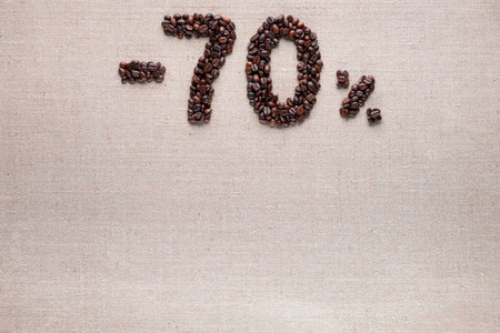 Roasted coffee beans shaping 70% off writing on creamy linen background, aligned top centerの写真素材