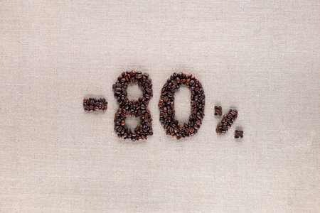 Roasted coffee beans shaping 80% off writing on creamy linen background, aligned in centerの写真素材