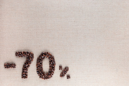 Roasted coffee beans shaping 70% off writing on creamy linen background, aligned bottom leftの写真素材