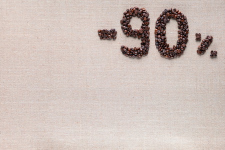 Roasted coffee beans shaping 90% off writing on creamy linen background, aligned top rightの写真素材