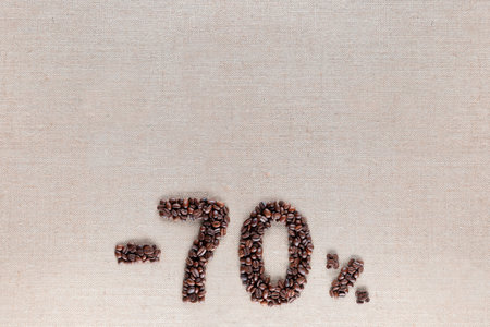 Roasted coffee beans shaping 70% off writing on creamy linen background, aligned bottom centerの写真素材