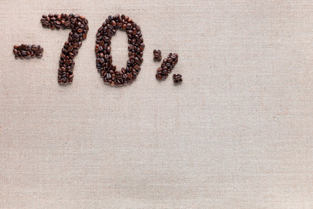 Roasted coffee beans shaping 70% off writing on creamy linen background, aligned top leftの写真素材