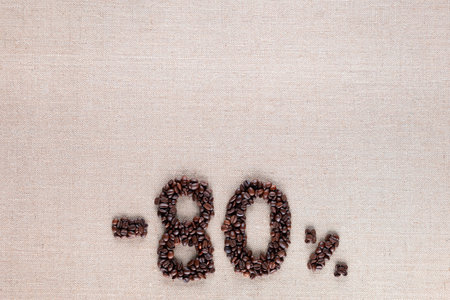 Roasted coffee beans shaping 80% off writing on creamy linen background, aligned bottom centerの写真素材