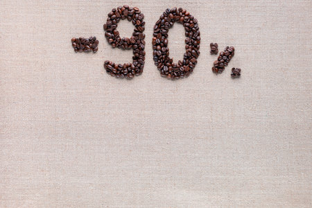 Roasted coffee beans shaping 90% off writing on creamy linen background, aligned top centerの写真素材