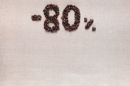 Roasted coffee beans shaping 80% off writing on creamy linen background, aligned top centerの写真素材