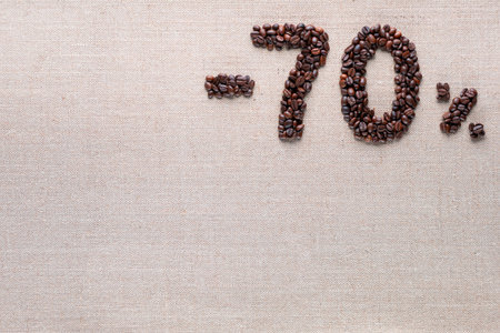 Roasted coffee beans shaping 70% off writing on creamy linen background, aligned top rightの写真素材