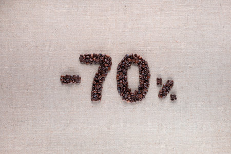 Roasted coffee beans shaping 70% off writing on creamy linen background, aligned in centerの写真素材
