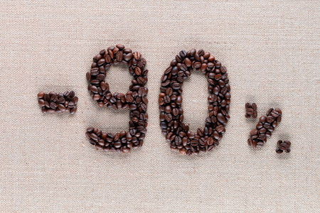 Roasted coffee beans shaping 90% off writing on creamy linen background, aligned in center, shot close upの写真素材