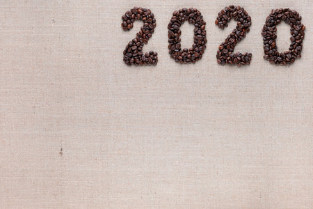 Bunch of fresh roasted coffee beans forming 2020 inscription on creamy linen canvas, aligned top rightの写真素材