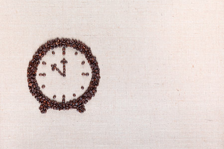 Round clock with stands made of roasted beans representing coffee time on linen surface, arranged to the leftの写真素材