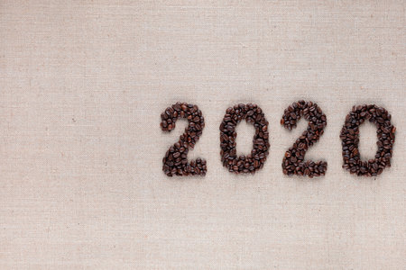 Bunch of fresh roasted coffee beans forming 2020 inscription on creamy linen canvas, aligned middle rightの写真素材