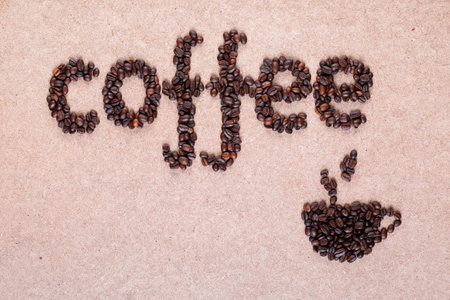 Steamy cup made of roasted beans placed on plywood surface near coffee wordの写真素材