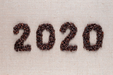 Bunch of fresh roasted coffee beans forming 2020 inscription on creamy linen canvas, shot close upの写真素材