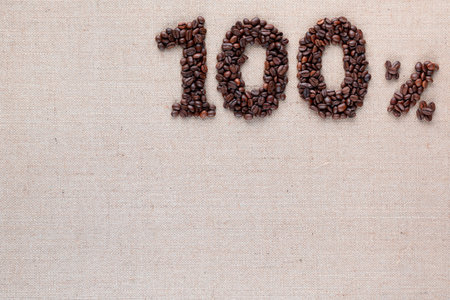 Roasted coffee beans shaping 100% off writing on creamy linen background, aligned top rightの写真素材