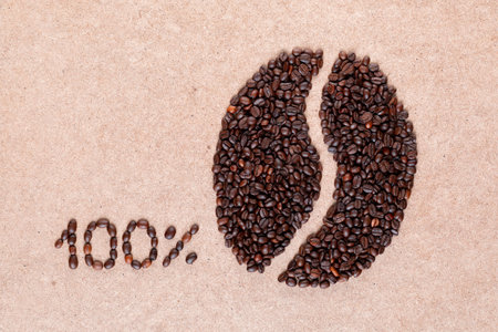 Bunch of roasted beans forming bean shape near a 100 percent sign on plywood surfaceの写真素材