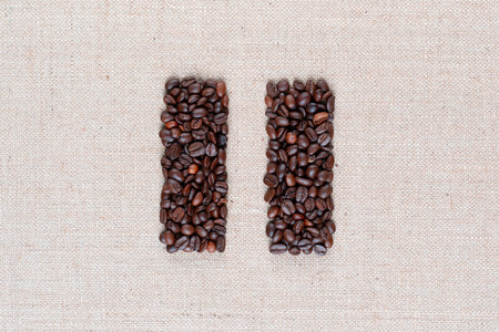 Bunch of roasted coffee beans forming pause symbol on creamy linen canvas, shot close up