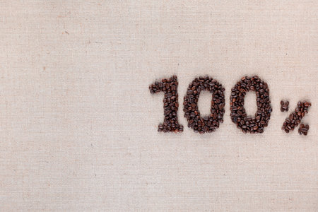 Roasted coffee beans shaping 100% off writing on creamy linen background, aligned middle rightの写真素材