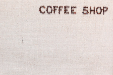 Bunch of roasted beans forming coffee shop inscription on gray canvas, aligned top rightの写真素材