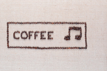 Coffee word and music note made of roasted beans inside border on linen surface, aligned middle leftの写真素材