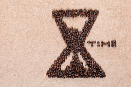 Bunch of coffee beans forming a sand clock with time inscription on plywood, aligned to the rightの写真素材
