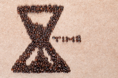 Bunch of coffee beans forming a sand clock with time inscription on plywood, aligned to the leftの写真素材