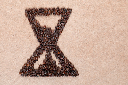Bunch of coffee beans forming a sand clock on plywood, aligned to the leftの写真素材