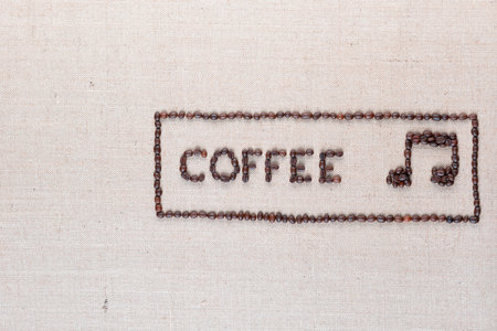 Coffee word and music note made of roasted beans inside border on linen surface, aligned middle rightの写真素材