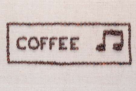 Coffee word and music note made of roasted beans inside border on linen surface, shot close upの写真素材