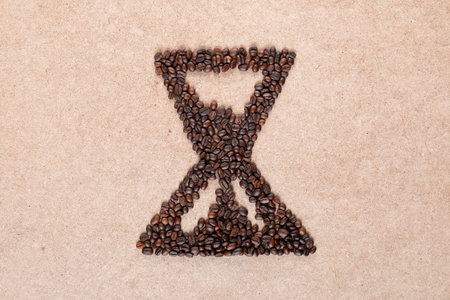 Bunch of coffee beans forming a sand clock on plywood, aligned in centerの写真素材
