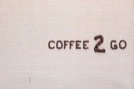 A lot of roasted seeds forming coffee to go writing against gray linen background, aligned middle rightの写真素材