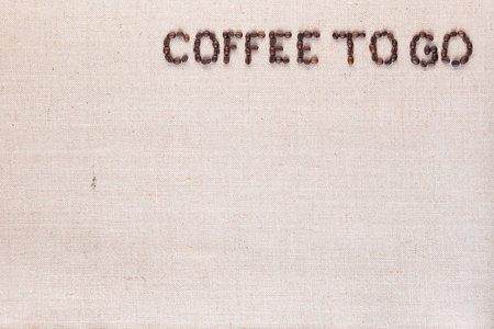 Coffee to go inscription made of roasted coffee beans on creamy linen canvas, aligned top rightの写真素材