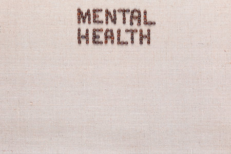 Mental health inscription made of roasted coffee beans placed on creamy linen texture, aligned top centerの写真素材
