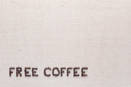 Free coffee written with roasted coffee beans on creamy linen texture, aligned bottom leftの写真素材