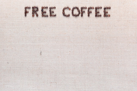 Free coffee written with roasted coffee beans on creamy linen texture, aligned top centerの写真素材