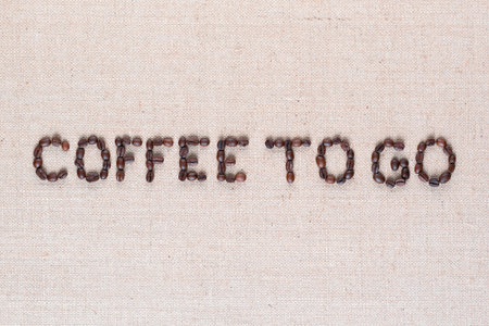 Coffee to go inscription made of roasted coffee beans on creamy linen canvas, shot close upの写真素材