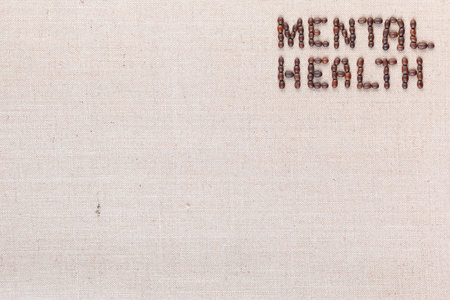Mental health inscription made of roasted coffee beans placed on creamy linen texture, aligned top rightの写真素材