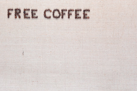 Free coffee written with roasted coffee beans on creamy linen texture, aligned top leftの写真素材