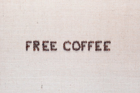 Free coffee written with roasted coffee beans on creamy linen texture, aligned in centerの写真素材