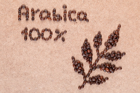 Close up of coffee branch and inscription promises 100% Arabica made of roasted beans on plywood surfaceの写真素材
