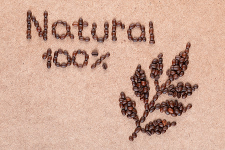 Close up of coffee branch and inscription promises 100% natural made of roasted beans on plywood surfaceの写真素材
