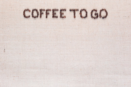 Coffee to go inscription made of roasted coffee beans on creamy linen canvas, aligned top centerの写真素材