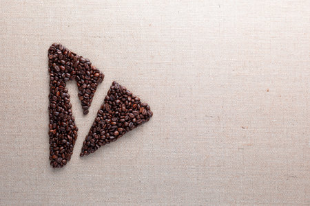 Letter y enclosed in triangle shape made of roasted coffee beans on creamy linen texture, aligned to...