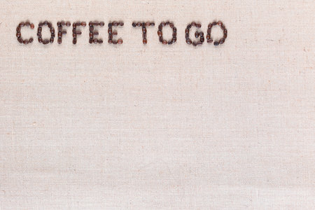 Coffee to go inscription made of roasted coffee beans on creamy linen canvas, aligned top leftの写真素材