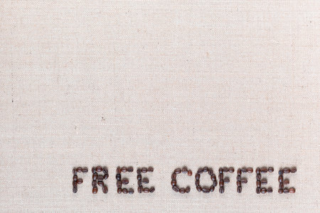 Free coffee written with roasted coffee beans on creamy linen texture, aligned bottom rightの写真素材