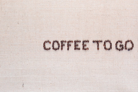 Coffee to go inscription made of roasted coffee beans on creamy linen canvas, aligned middle rightの写真素材