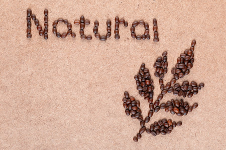 Close up of coffee branch and inscription natural made of roasted beans on plywood surfaceの写真素材