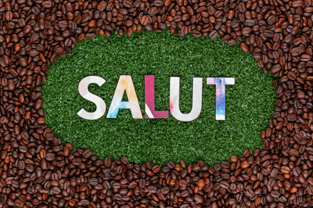 Close up of salut word made from colorful letters on artificial grass surrounded by roasted coffee beansの写真素材